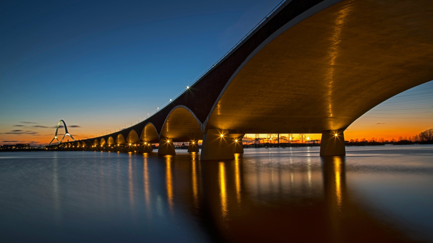A sunset with a bridge over water.